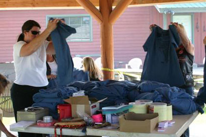 Women folding stacks of Ride for Life t-shirts onto tables.