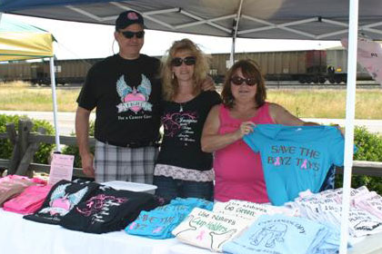 Several people pose with a table full of custom t-shirts.