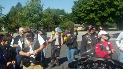 People standing in the parking lot while wearing their riding gear.