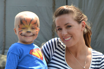 Woman holding a child with a painted face.