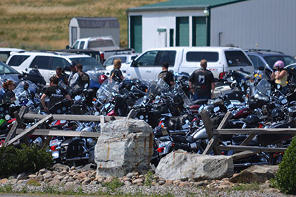 People in a parking lot filled with motorcycles and vehicles.