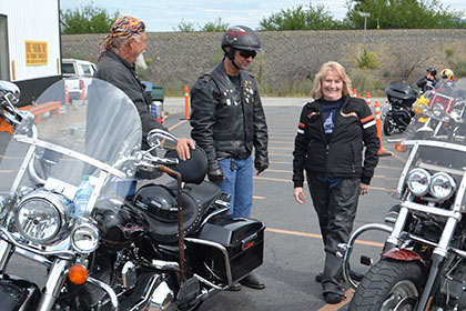 Some riders standing next to their motorcycles.