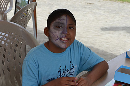 Child with their face painted, plays a board game.