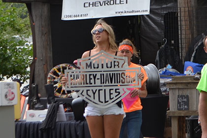 Woman showcasing Harley-Davidson sign next to some Ride for Life committee members.