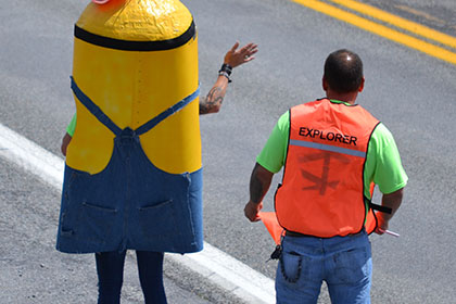 Ride for Life committee member and Minion stand on side of the road.