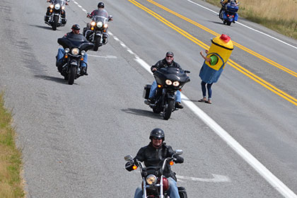 A Ride for Life committee member waives in riders.